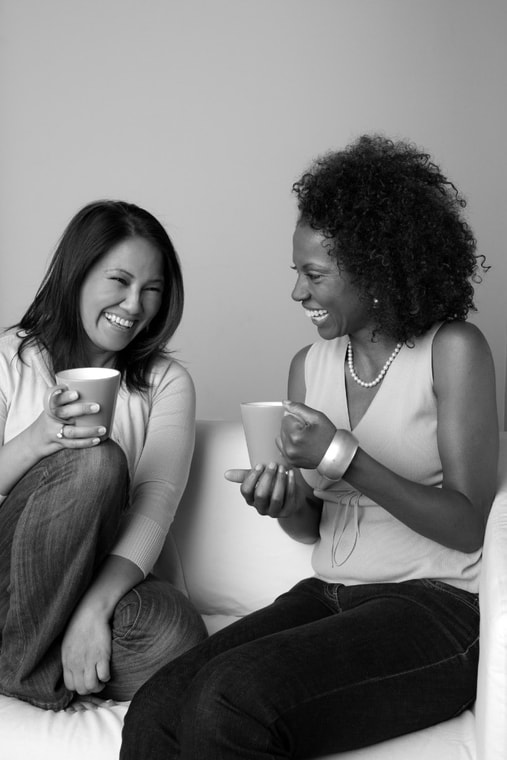 two women of different nationalities, drinking coffee and laughing together